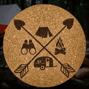 Round natural camping adventure cork coaster featuring a laser-engraved crossed arrow design with a tent, binoculars, campfire, and camper trailer.