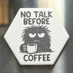 A white hexagon funny coffee ceramic magnet featuring a groggy monster with a mug and text reading No Talk Before Coffee