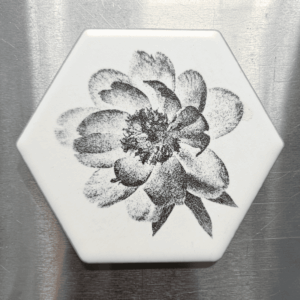A white hexagon peony flower ceramic magnet featuring a detailed black stippled illustration of a blooming peony flower