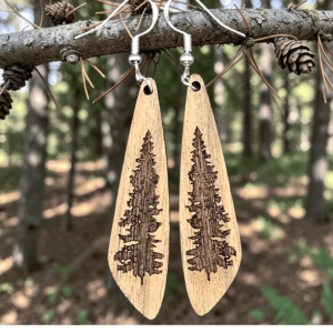 A pair of handcrafted pine tree wood earrings featuring detailed etched evergreen trees