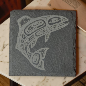 Square salmon slate coaster etched with Indigenous-style formline salmon artwork on dark stone.