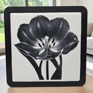 A framed tulip ceramic tile coaster with detailed black and white floral engraving